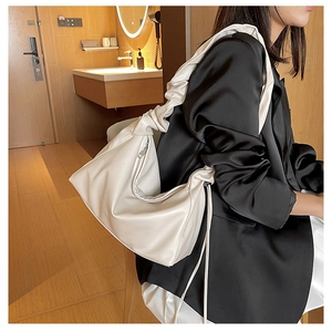 Close-up of cream scrunchie strap shoulder bag styled with professional black blazer dress