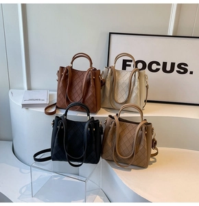 Detail of four woven bucket bags in various colors displayed on white stairs