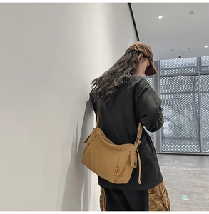 Détail du sac messager en toile kaki avec poche latérale et bandoulière réglable