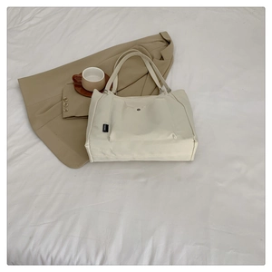 Detailed view of cream canvas tote bag with large front pocket and long handles