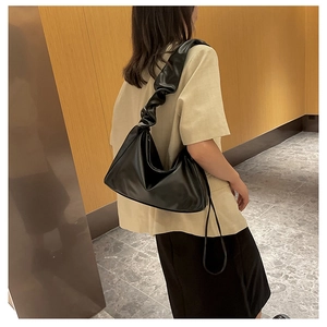 Detail of black pleated hobo bag with stylish accordion shoulder strap on female model