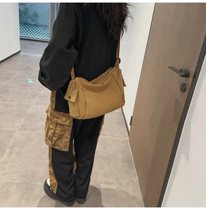 Détail de la besace en toile kaki avec poche latérale à pression sur un mannequin