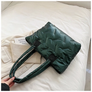 Detail of dark green puffer tote bag with V-shaped quilting and glossy nylon texture