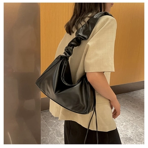 Detail of black pleated shoulder bag with ruched strap texture in modern interior