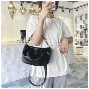 Detail of black pleated cloud bag with leather texture, chain handle and adjustable strap