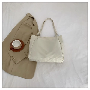 Close-up of beige nylon tote bag with silver ring buckles and slim shoulder straps