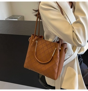 Detail of brown quilted leather tote bag featuring U-shaped metal handles and textures