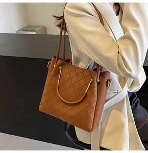 Brown leather tote bag featuring quilted stitching and metal handles on a model