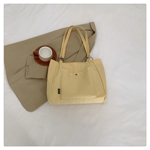 Detail of beige canvas tote bag showing front snap pocket and branded CHIQIMEL label