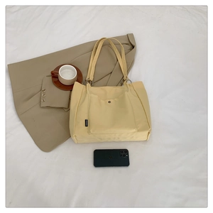Close-up of yellow canvas tote bag with snap-button front pocket and sturdy metal rings