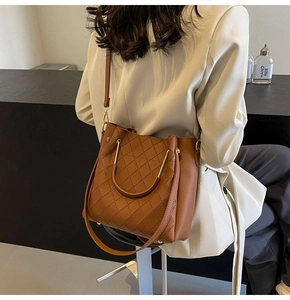 Detail of brown quilted bucket bag featuring a gold metal handle and luxury faux leather texture