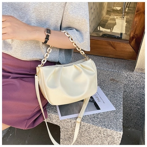 Detail of off-white ruched dumpling bag with acrylic chain and leather shoulder strap