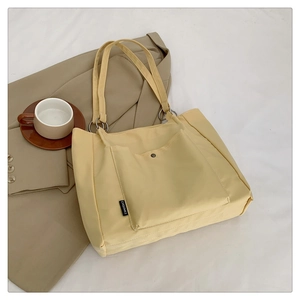 Detail of yellow canvas tote bag with front pocket, metal ring and CHQIMEI woven label