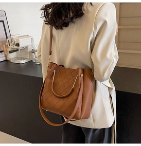 Close-up of a brown quilted bucket bag with a metal handle shown in a social setting