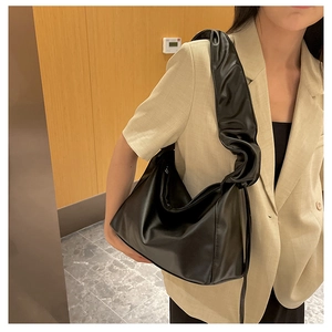 Detailed view of the ruffle pleated strap on a black PU leather baguette shoulder bag