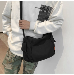 Détail d'un sac messager en toile noire avec poche latérale et bandoulière réglable pratique