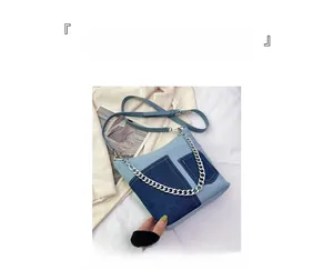Detail view of denim patchwork bucket bag with silver metal chain and thin shoulder strap