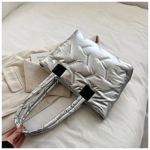 Close-up of silver quilted puffer tote bag featuring unique V-shaped metallic texture details