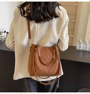 Close-up of brown litchi PU leather bucket bag with gold metal handle and quilted stitching