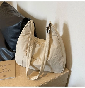 Macro detail of creamy nylon hobo bag with wide shoulder strap and black adjustment buckle