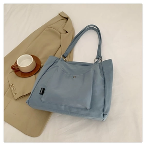 Detailed view of the light blue canvas tote bag featuring front snap pocket and silver rings