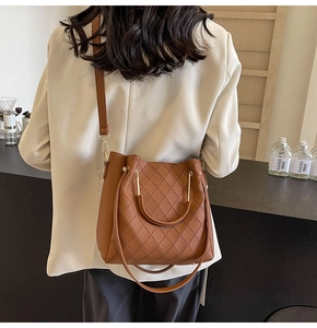 Detailed view of brown quilted bucket bag with curved metal handle on a person