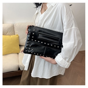 Dettaglio della pochette a busta nera con borchie quadrate argento e trama stropicciata