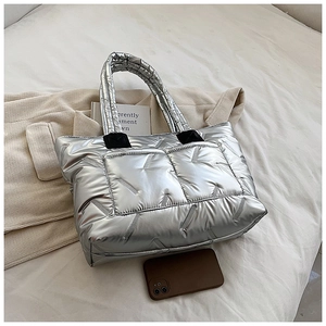 Detail of silver quilted tote bag showing metallic texture and reinforced handle stitching