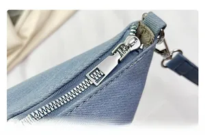 Close-up of the silver metal zipper and blue leather strap on a canvas bucket bag