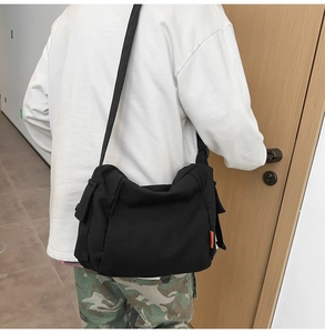 Vue arrière du mannequin portant un sac messager en toile noire avec bandoulière réglable