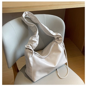 Close-up of white gathered strap shoulder bag with silver zipper on a soft seat