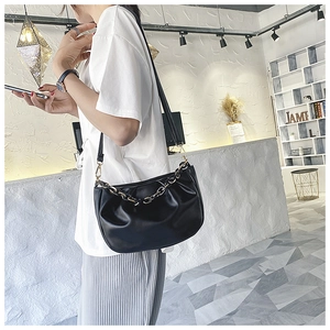Detail view of the black pleated cloud bag with its woven gold chain and soft PU leather