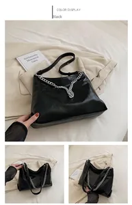 Detail of black soft leather tote with silver chain accent on neutral background