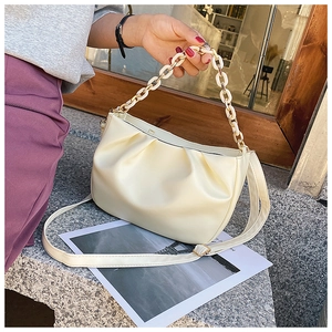 Detail of creamy white pleated cloud bag with stylish acrylic chain and smooth leather texture