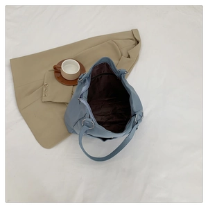 Detail view of high-capacity tote bag with metal rings and deep brown inner lining