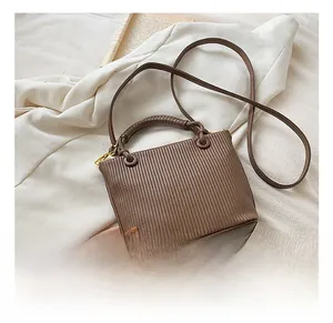 Detail of pleated texture on brown bucket bag with braided handle and gold metal hooks