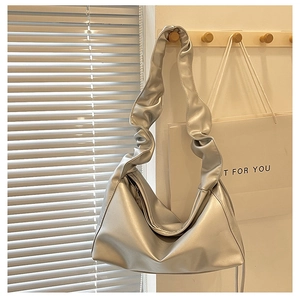 Close-up of metallic silver crescent bag with pleated scrunchie strap and zip closure