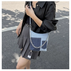 Detail of denim patchwork shoulder bag featuring silver chain and dark blue pockets