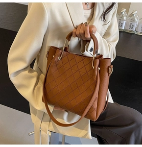 Macro detail of brown leather bucket bag featuring quilted diamond pattern and metal handle