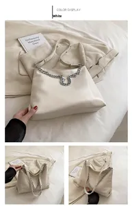 Detail of white leather tote bag featuring a chunky silver metal chain strap and soft texture
