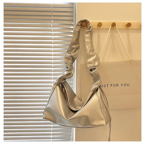 Detailed view of silver baguette bag featuring pleated shoulder strap and metallic finish