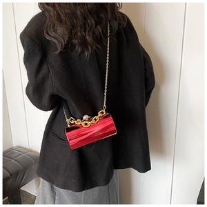 Detail of red acrylic mirror cylinder bag with gold chain and large pearl handle