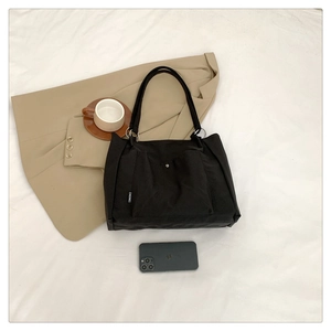 Detailed view of black canvas tote bag with front pocket and metal ring handle connection