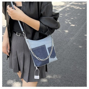 Close-up of trendy patchwork denim bucket bag with silver chain and dual pockets