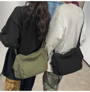 Détail du grand sac messager en toile avec bandoulière réglable et poches latérales