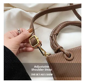 Detail of adjustable strap and golden metal buckle on brown pleated hobo bag