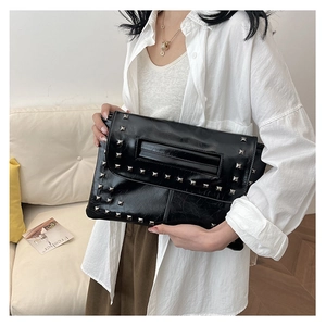 Dettaglio della pochette a busta in pelle verniciata nera con borchie quadrate argento