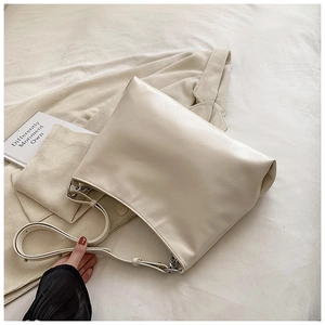 Close-up of cream soft leather tote bag with silver buckle on neutral fabric background