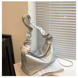 Close-up of matte silver crescent baguette bag with ruched handle on minimalist background