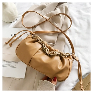 Gros plan d'un sac nuage plissé beige avec chaîne en acrylique sur fond neutre